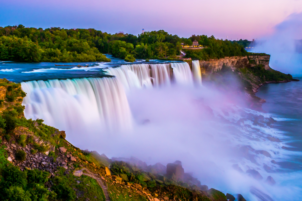 View of Niagara Falls in the sunset hours with colors washing over the falls, which are one of the best family vacation destinations for all ages