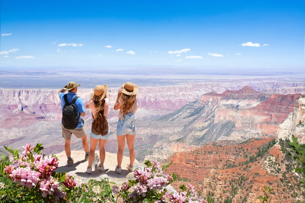 Family of 3 standing in the North Rim of Grand Canyon National Park with backpacks and hats on during spring, showing one of the best spring break destinations for families