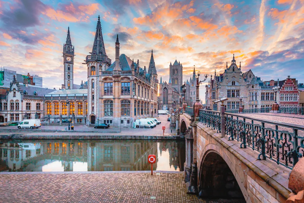 Stunning view of the city center in Ghent, a top pick for best places to stay in Belgium, with its towering cathedral and picturesque stone walkways, as seen from across a stone bridge