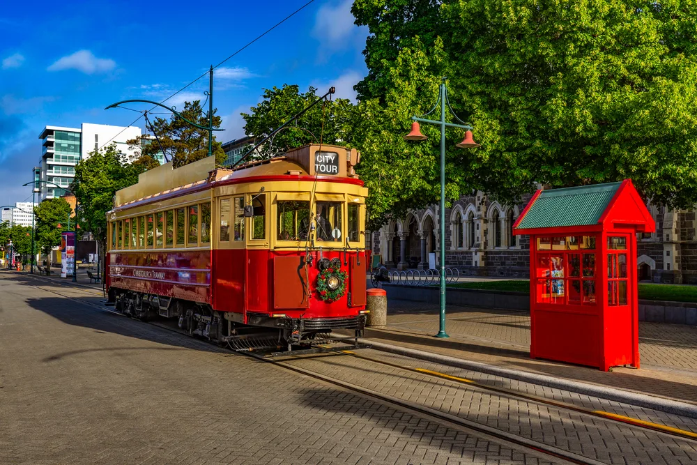 Neat cable car with wooden panels makes its way down a picturesque brick street in Christchurch, one of our top picks for the best areas in New Zealand