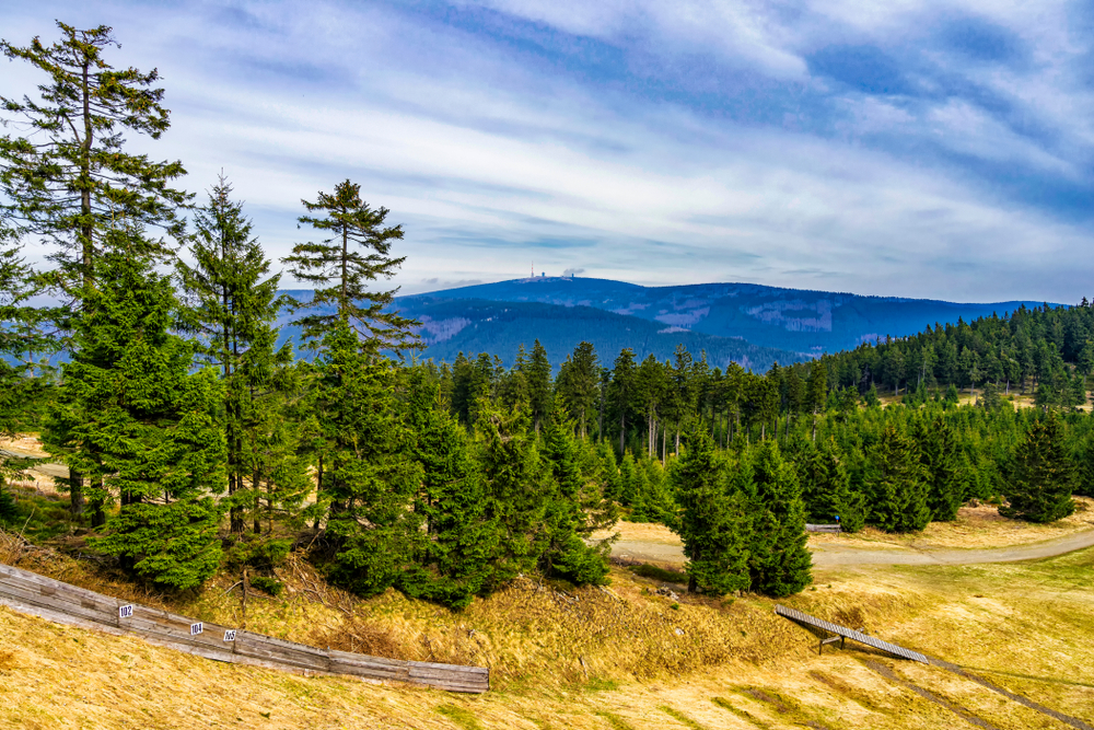 Distant view of the Brocken mountain in the Harz Mountains range with alpine trees in the foreground for a list of Germany's top mountains