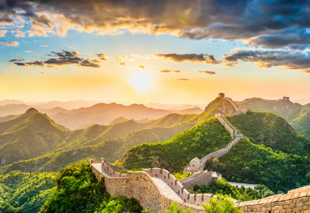 The Great Wall of China seen from above at sunrise with clouds in the sky for a list of FAQs on bucket list travel ideas worldwide