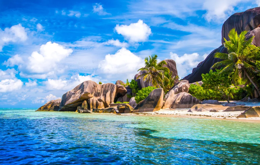 Source d'Argent Beach at La Digue Island in Seychelles is one of the top honeymoon destinations in the world, shown with boulders and greenery on the beach