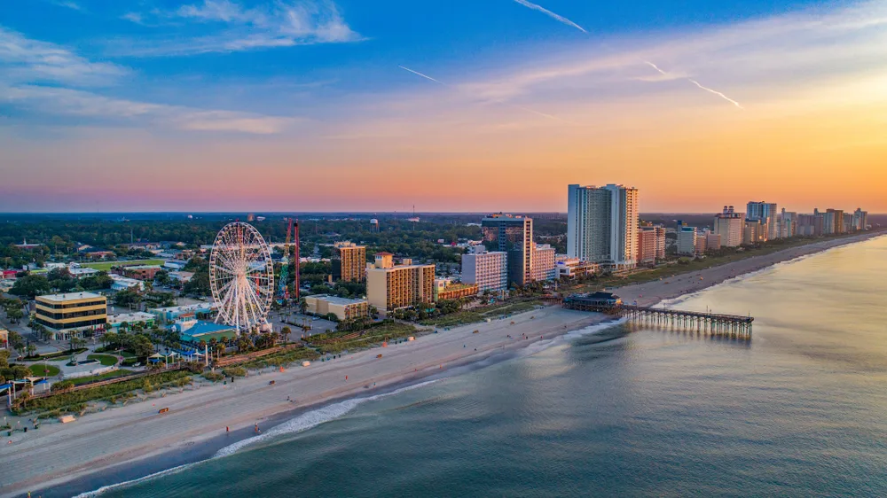 Myrtle Beach boardwalk and pier seen from an aerial view at sunset with nearly empty beaches for a list of the best East Coast vacations spots