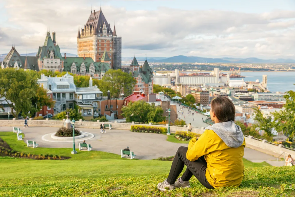 Woman sitting on a grassy hill for a guide to the average cost for a trip to Canada