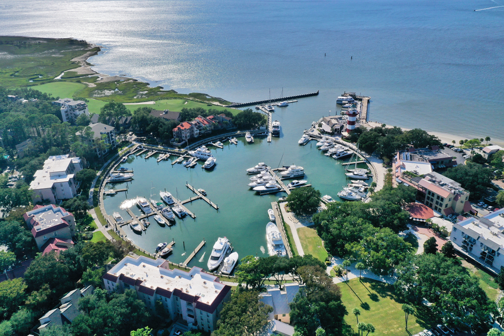Hilton Head Island's Harbour Town Marina aerial view with golf course and shore in view as boats dock in the marina at one of the best spring break spots in the US for families