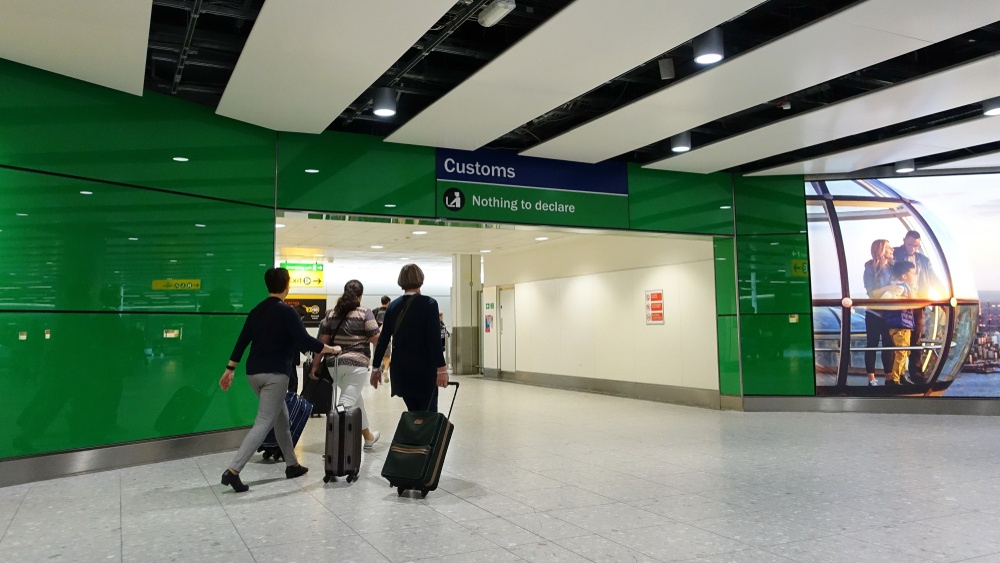 Passengers going toward the green "Nothing to declare" customs corridor at London's Heathrow Airport for a piece answering what is customs at the airport?