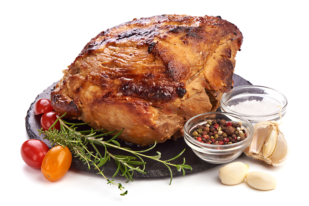 Bavarian beer-roasted pork seen with juniper berries, rosemary, and garlic isolated on a platter in front of white background for a list of the best German food to try