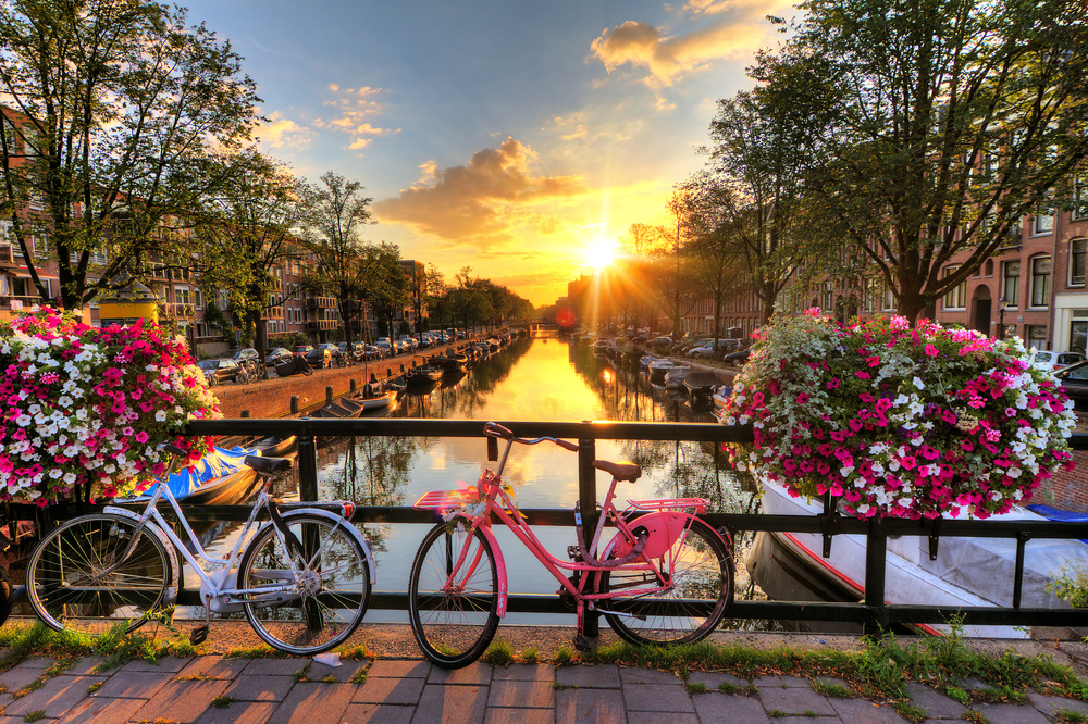 Gorgeous sunrise over bikes on a bridge in Amsterdam for a guide to what a trip to the city costs