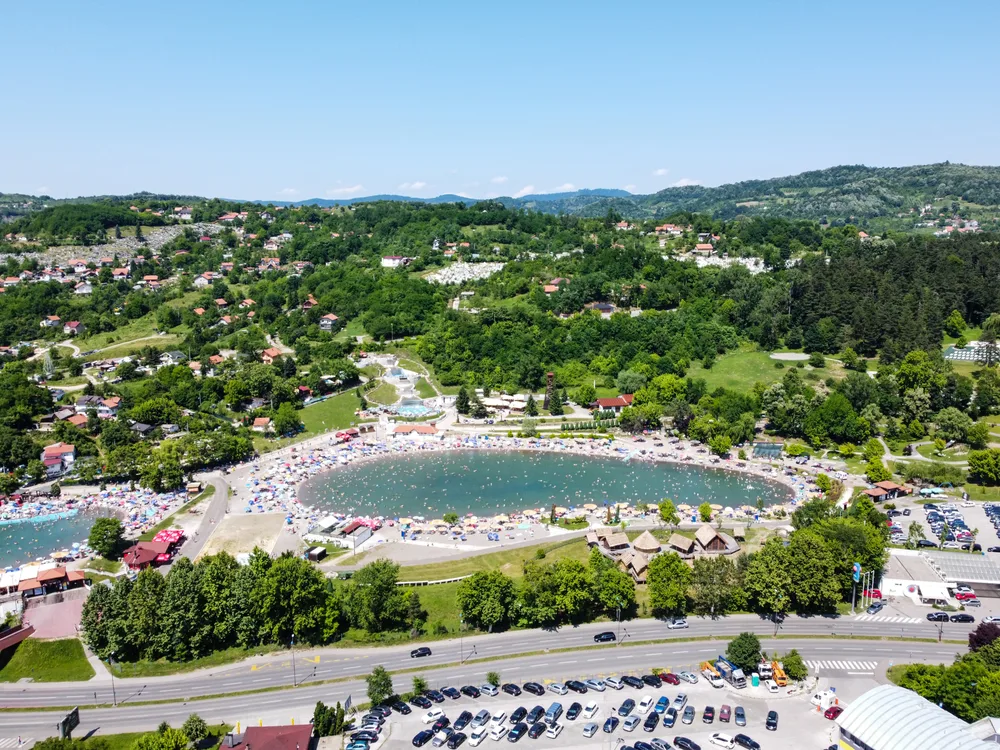 For a guide to the best places to stay in Bosnia, an aerial image of the Pannonian Lakes complex in Tuzla with lots of people swimming in the water