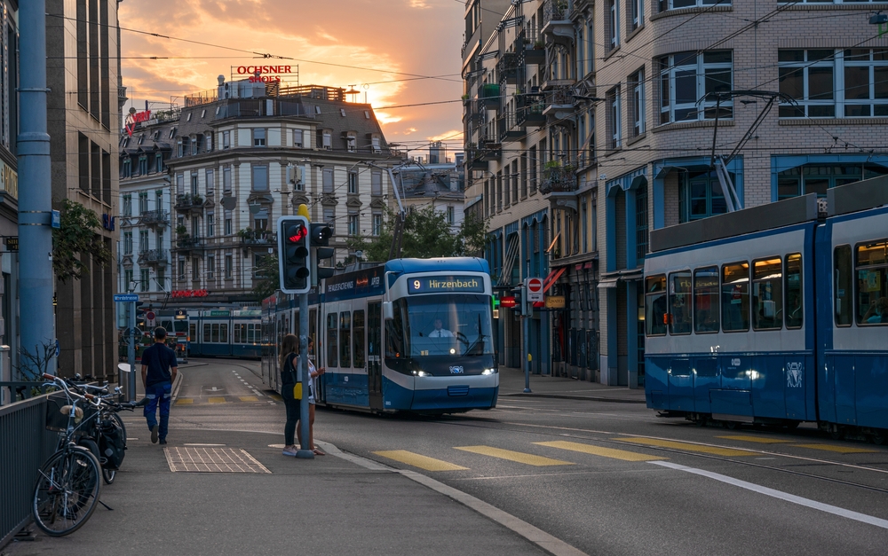 Blue and white tram in Zurich, pictured during the best time to visit, making its way down the street at dusk