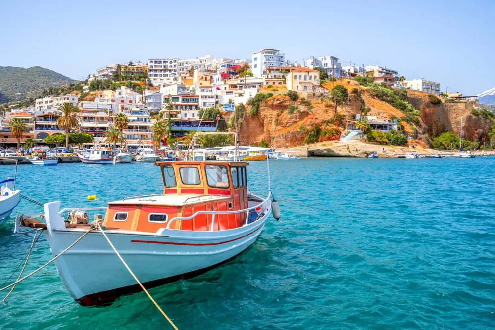 Boat floating on crystal-clear water on Agia Galini as an image for a guide to what a trip to Greece costs