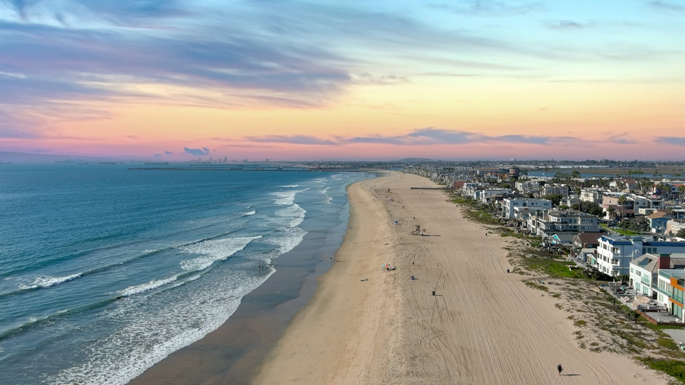 Aerial view of Huntington Beach, California at sunset with clouds overhead and waves hitting the shore for a list of the best beach destinations 