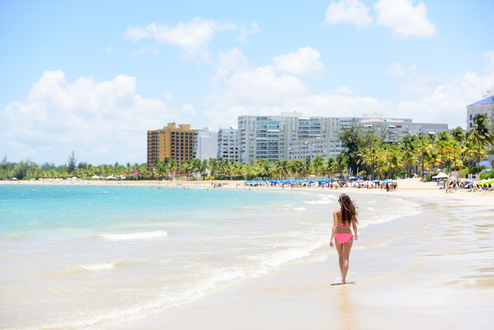 Attractive woman in a pink bikini walking along the beach on Isla Verde in Puerto Rico