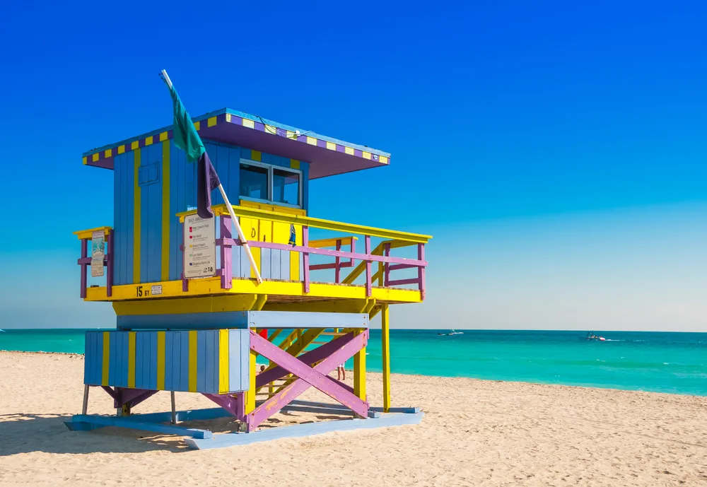 Colorful vintage lifeguard tower on South Beach in Miami Beach, Florida with bright aqua water visible beyond the sand for a list of the best beach vacations