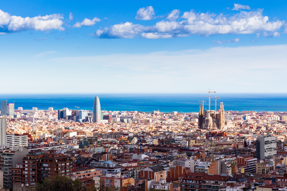 Barcelona skyline indicates this is one of the best cities to visit in Europe with Sagrada Familia and the coast visible from an aerial view