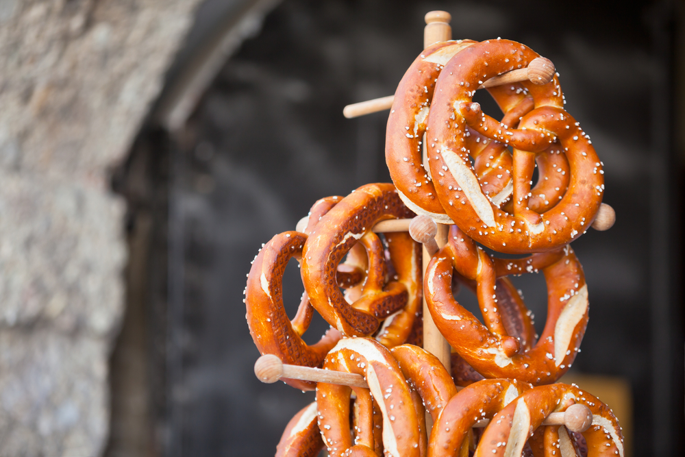 German pretzels hanging fresh on a pretzel wooden stand with salt on them for a piece showing the best German food to try