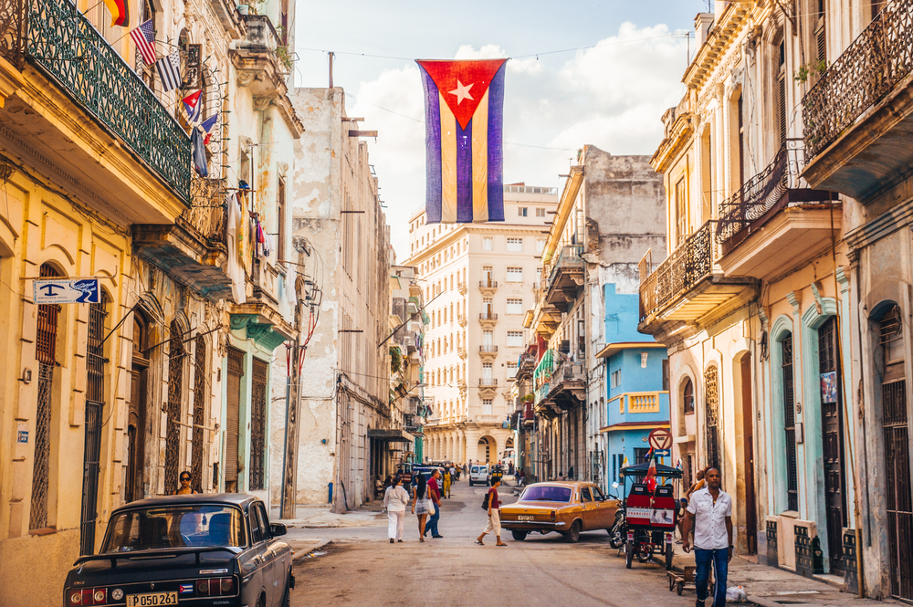 Photo of a flag with holes waving in the streets of Havana pictured for a guide titled Trip to Cuba Cost