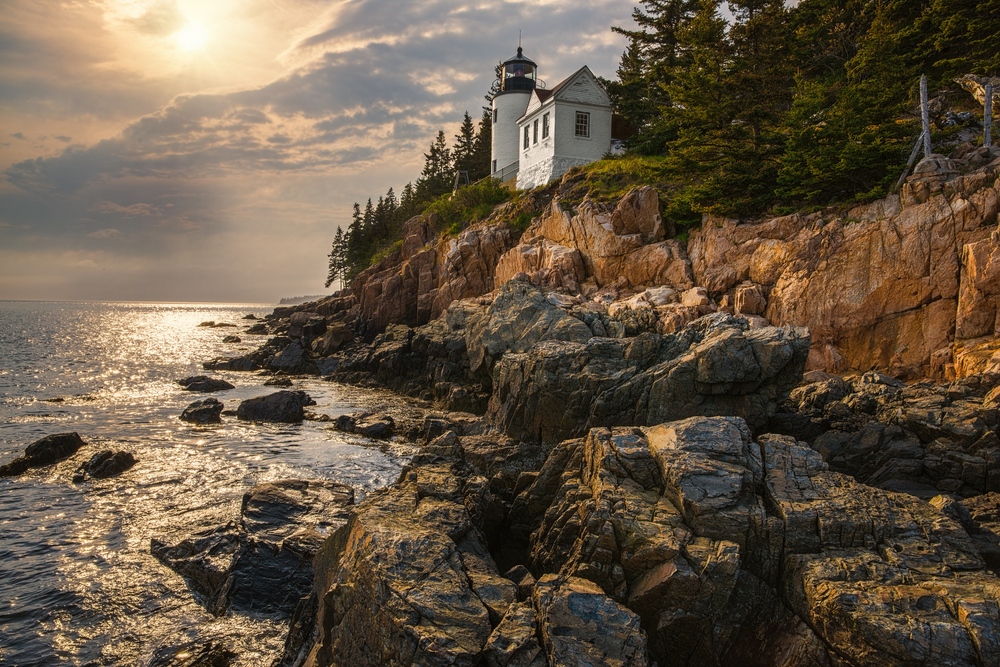 Bar Harbor rocky coast with a lighthouse shown at sunset to show one of the top places for a couples vacation in the US