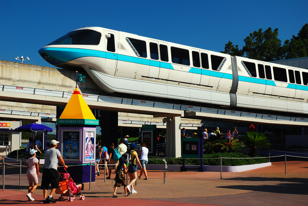 Photo of the monorail pictured running above people walking along the street in Disney World for a piece on the average cost to go