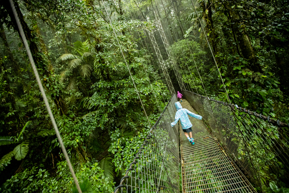 Kids walk on a suspended bridge during a canopy tour through the rainforest in Costa Rica, one of the best family vacations for all ages