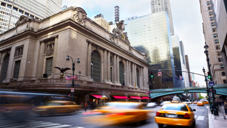Taxis making their way down the street in front of Grand Central station in downtown NYC for a guide titled Trip to New York Cost
