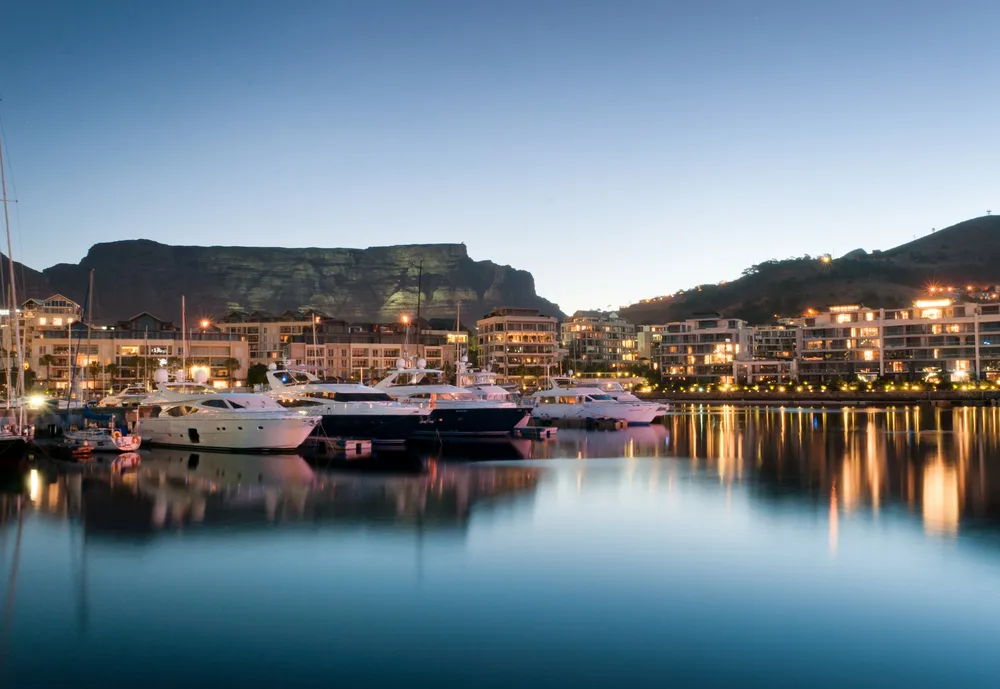 A calm image of boats docked on a pier with still waters at the Victoria and Alfred Waterfront, a top pick for where to stay in Cape Town, on a still night