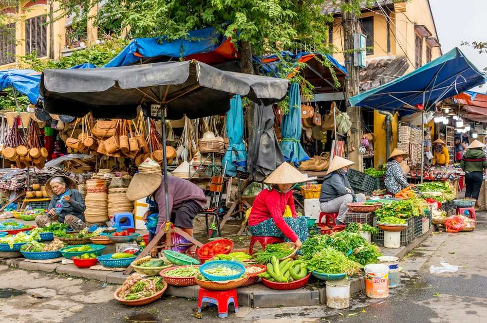 Local vendors can be seen arranging their items on the side of the street, where they can be seen selling various vegetables. 