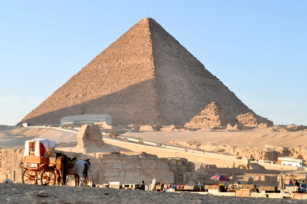Photo of the Great Pyramid of Giza pictured behind a horse-drawn carriage