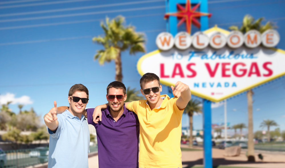 Group of 3 guy friends in Las Vegas in front of the iconic sign for a list of the best guys trip ideas