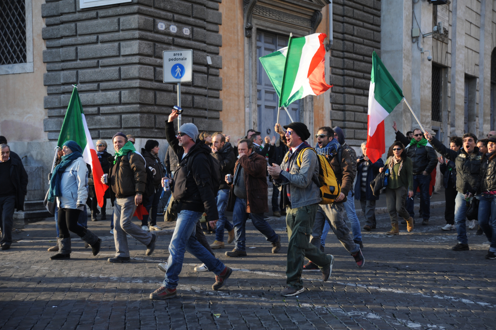 People can be seen protesting while holding an Italia flag. 