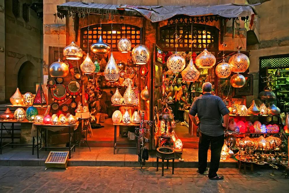 A man standing in front of a store that sells house hanging ornaments. 