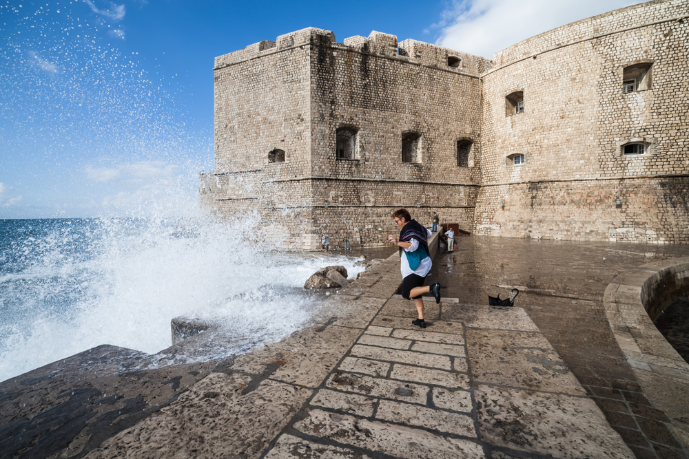 Waves crash against the walled town of Dubrovnik