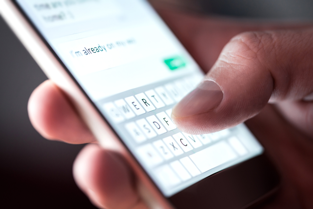 Close-up of a person text messaging on a smartphone for an article asking how much does it cost to text internationally?
