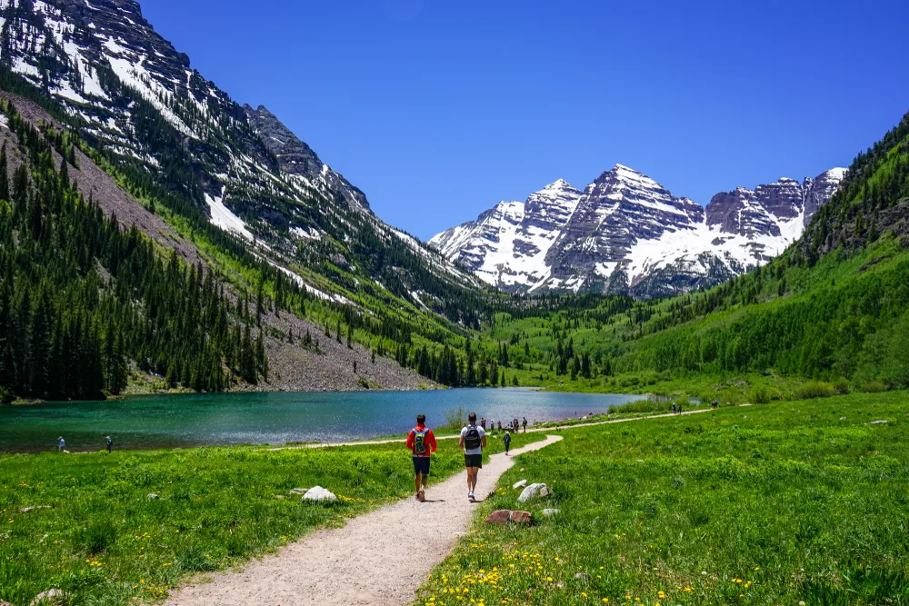 Two hikers walking along a gravel path in Maroon Bells near Aspen for a guide titled Where to Stay in Colorado