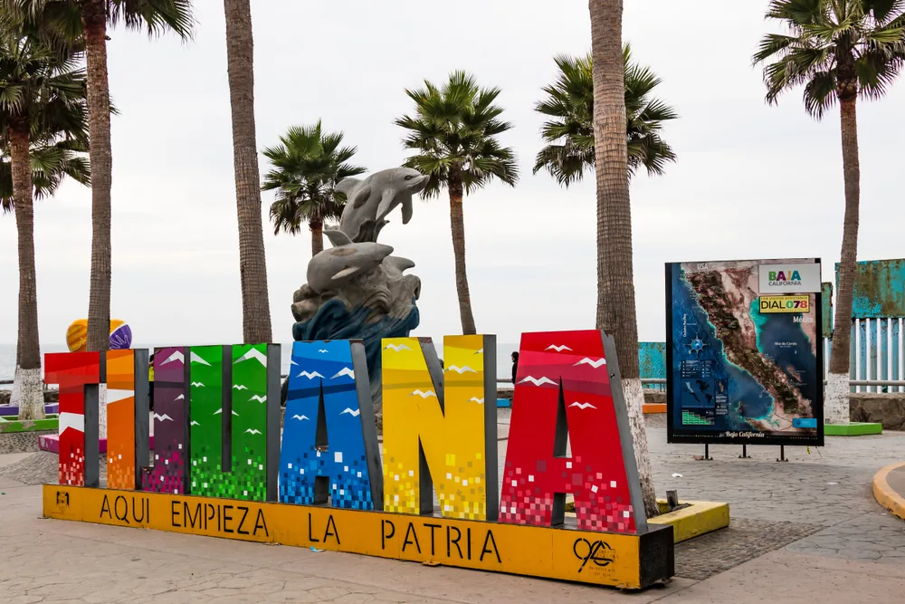 A vibrant Tijuana type signage standing in front of a dolphin statue. 