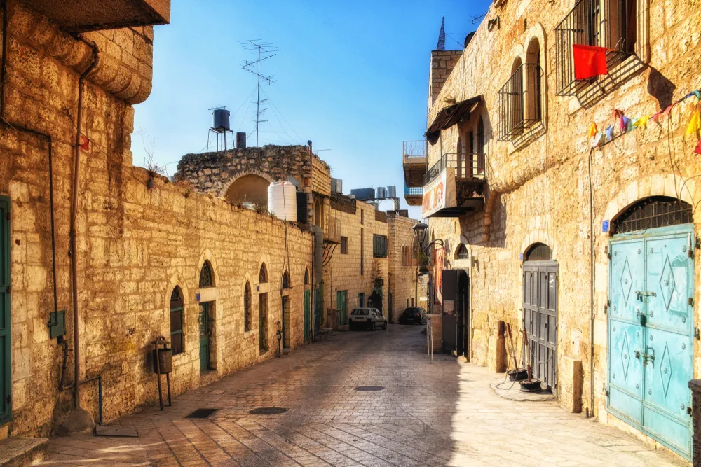 La Calle Estrella in Bethlehem pictured for a guide on whether or not Palestine is safe to visit, pictured with its tall walls under a blue sky and a brick street in the middle of the scene