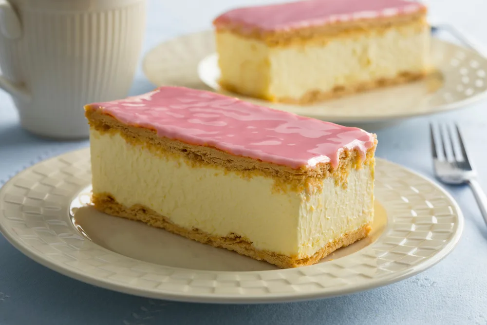 Tompouce cake with pink icing on a white plate, shown as a candidate for the best Dutch food to try
