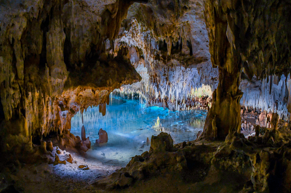 A magnificent cave with clear water on the ground, spiky rock formations. 