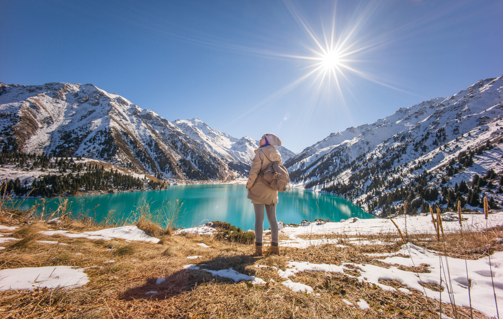 Woman standing on a hillside overlooking the Big Almaty Lake, as seen during the least busy time to visit Kazakhstan, the winter