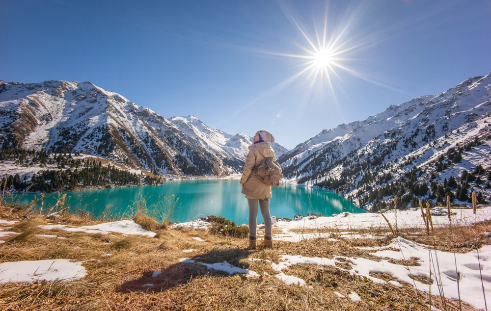 Woman standing on a hillside overlooking the Big Almaty Lake, as seen during the least busy time to visit Kazakhstan, the winter