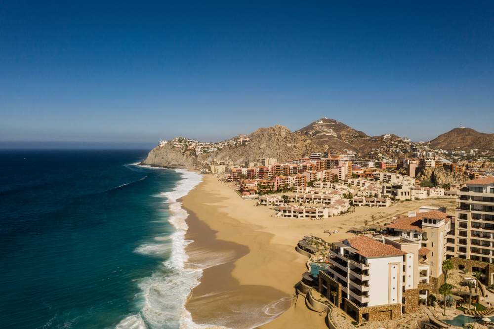 Aerial view of the deep blue water pictured running along the empty sandy beach in Pedregal, one of the best areas to stay in Cabo