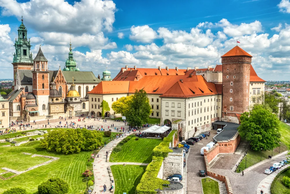 Wawel Castle in Krakow, Poland during a beautiful day with tourists around and blue cloudy skies overhead as one of the cheapest places to travel in Europe