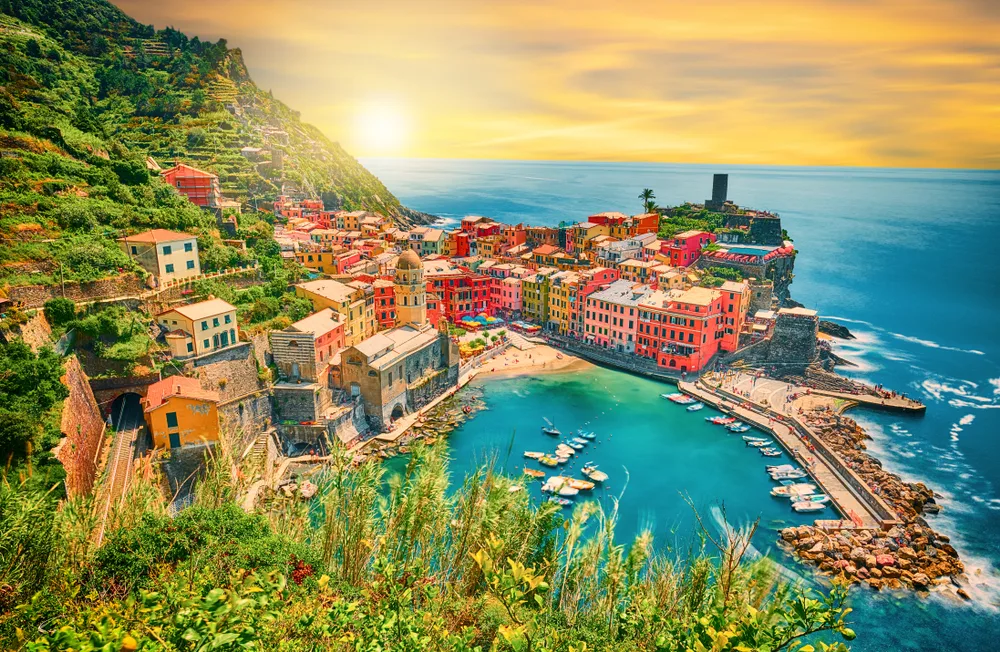 Aerial view of the village of Vernazza in Italy's Cinque Terre at sunset with the harbor and boats in view of the colorful houses