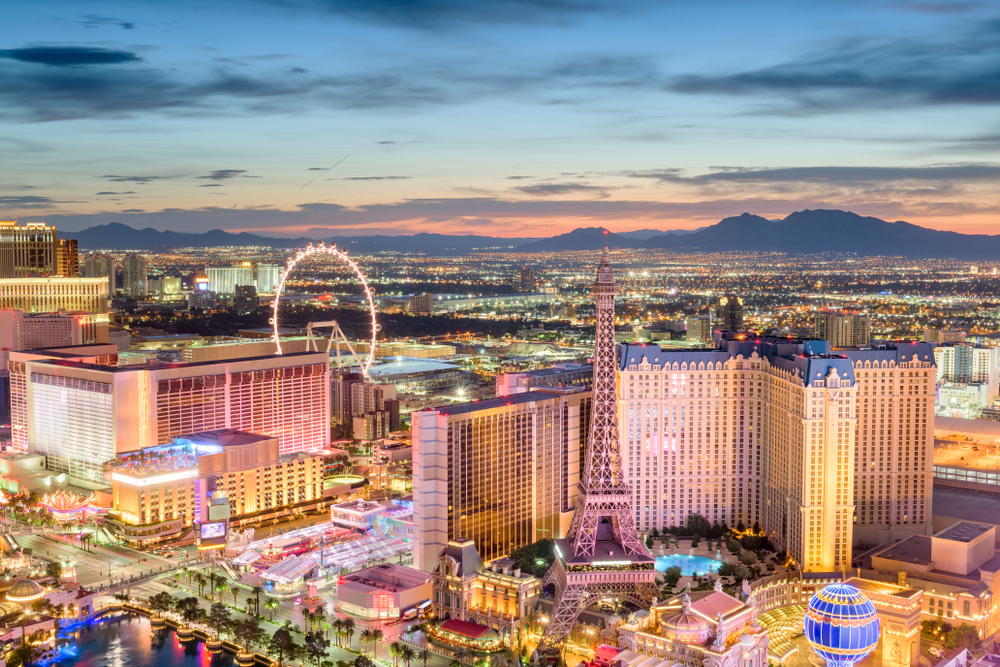 Aerial view of Las Vegas at dusk with casinos and hotels illuminated in neon lights