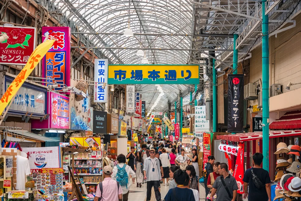 A crowded market area in Japan where people as seen passing by in front of various stores. 