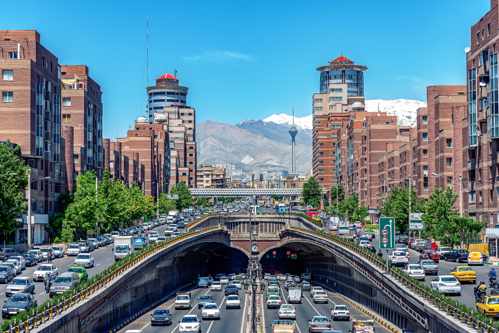 Neat view of Tehran with its picturesque downtown skyline towering over the street with snow-capped mountnains in the background during the cheapest time to visit Iran, the winter