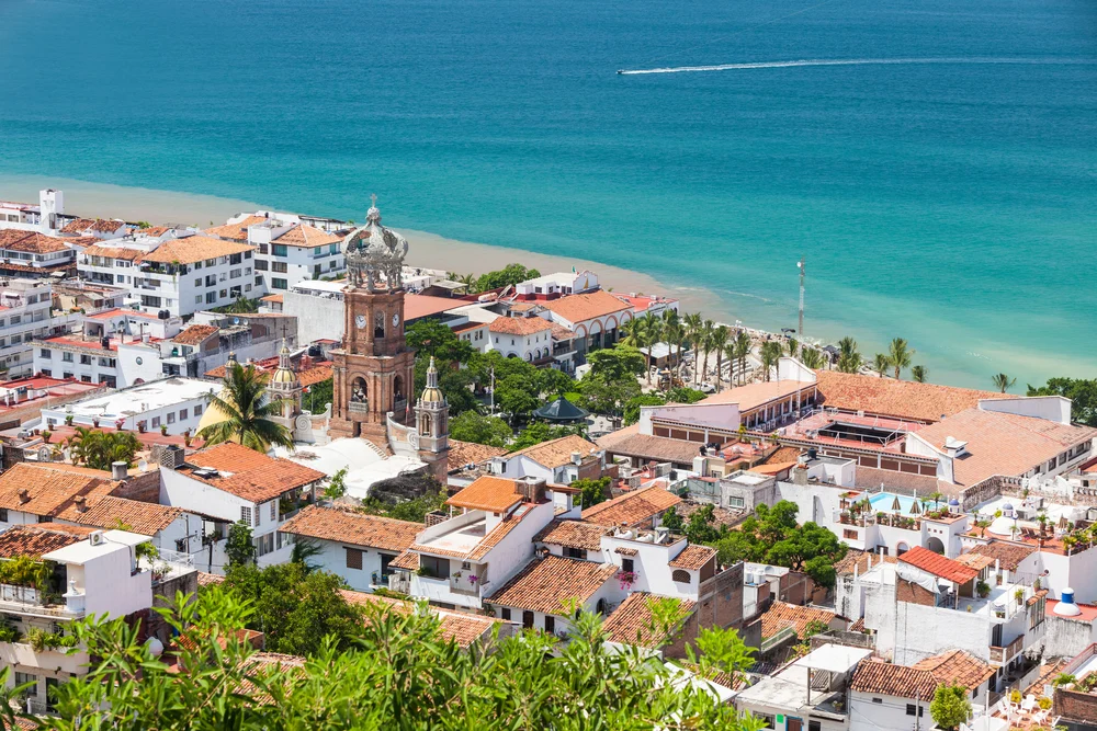 Orange roofs of buildings situated near the emerald color beach can be seen from above.