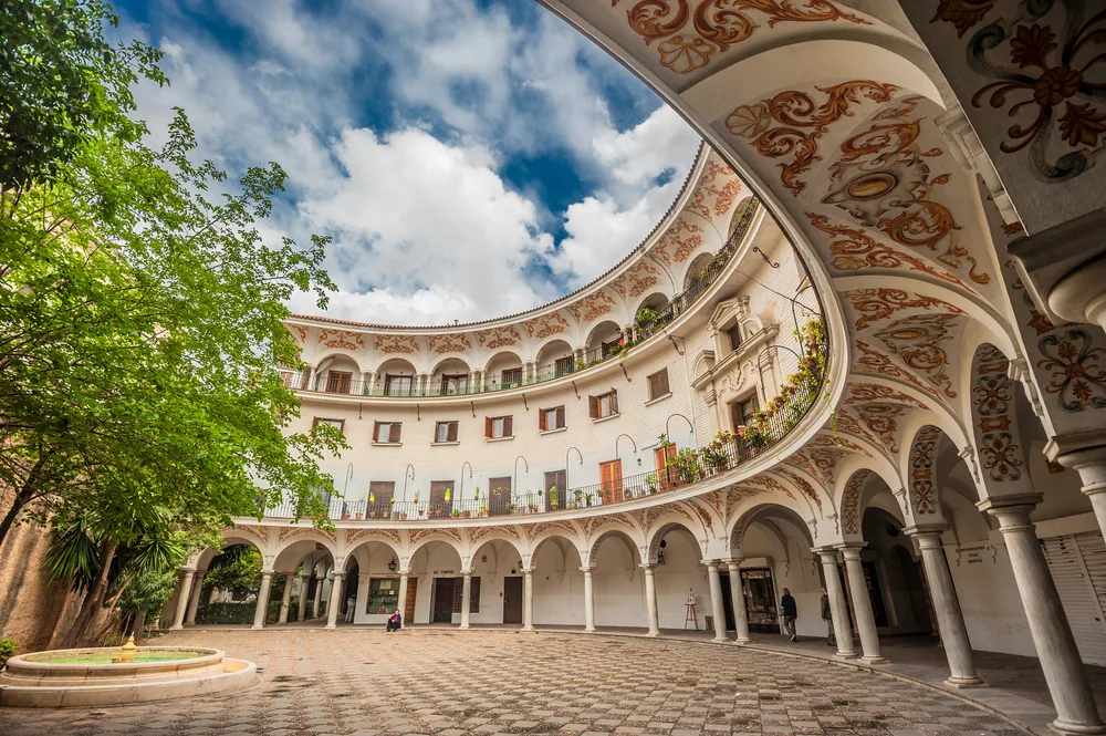 A historical building in El Arenal, our pick on the best areas to stay in Seville, the round center of a building has an intricate designs on the ceiling.