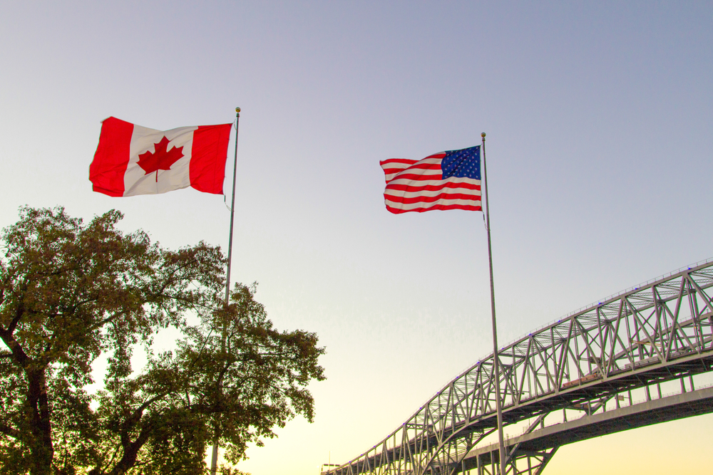 USA and Canada flags waving at the trans-border crossing between Port Huron, MI and Sarnia, Ontario for an article answering what is domestic travel